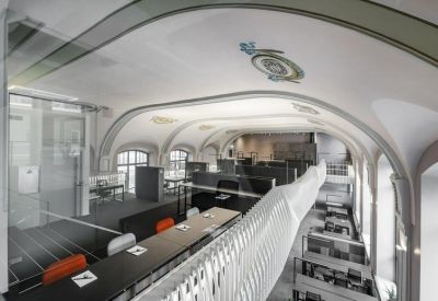 Spacious open-plan workspace under a vaulted ceiling with historic decorative details.