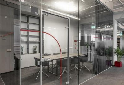 Professional meeting room enclosed in glass with a long table and black ergonomic chairs.