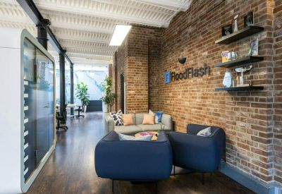 Reception lounge area with navy blue armchairs and brick feature wall.