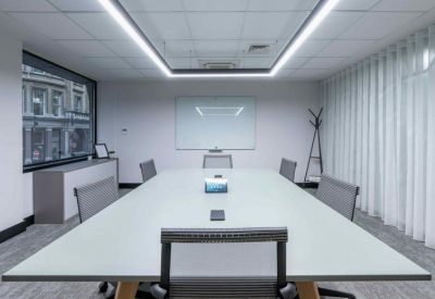 Minimalist conference room with a large white table and integrated ceiling lighting.