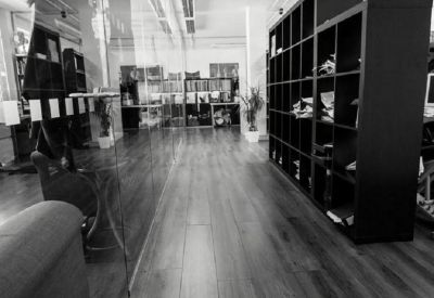 Black and white view of a long hallway with wood flooring and tall shelving units.