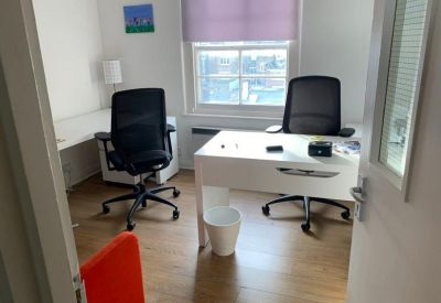 Private office featuring two white desks, black chairs, and a large window.