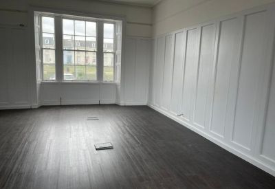 Spacious office suite featuring dark wood flooring and white wood-paneled walls.