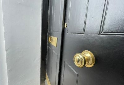 Detailed view of a brass door handle and letterbox on a black paneled door.