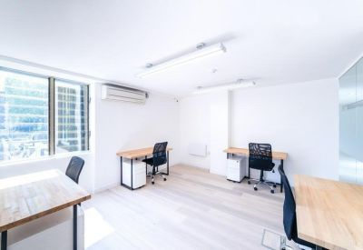 Bright private office suite with three wooden desks and views of the city buildings.