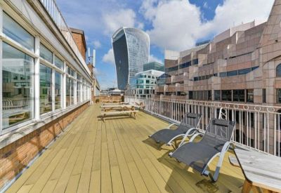 Spacious rooftop terrace with wooden decking, lounge chairs, and views of city skyscrapers.