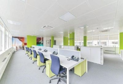 Bright open-plan office with white desks, blue chairs, and lime green accent pillars.