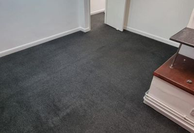 Spacious carpeted office room with white walls and an open doorway.