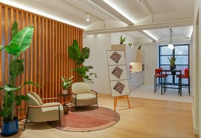 Bright communal lounge with wood-slat feature wall, comfortable armchairs, and a view into a kitchen area.