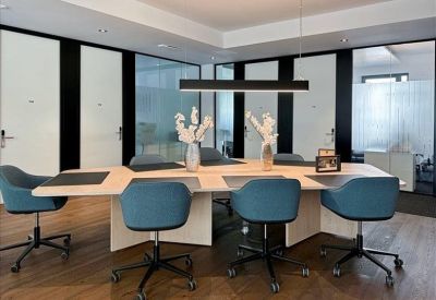 Bright communal break area with a high wooden table and blue upholstered seating.