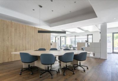 Modern meeting room featuring a large white table, blue chairs, and a wood-paneled wall.