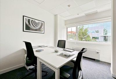 Bright private office suite with two black chairs and a framed abstract print.