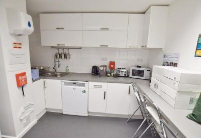Compact communal kitchen with white cabinetry, a dishwasher, and a breakfast bar.
