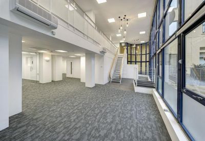 Bright, open-plan reception lobby with grey carpeting and high ceilings.
