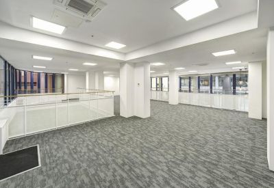 Spacious open-plan office area with large windows and bright recessed lighting.