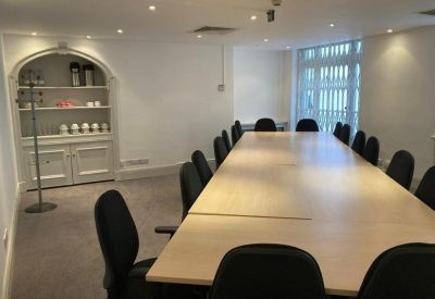 Long boardroom table with black chairs and a recessed arched shelving unit.