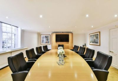 Spacious boardroom with a large light wood table and black leather chairs.