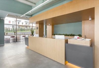 Modern reception area with a minimalist wooden front desk and large glass window.
