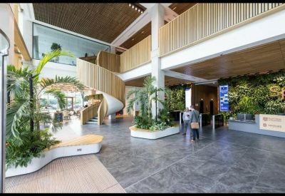 Spacious modern lobby featuring a spiral staircase, indoor trees, and a living green wall.