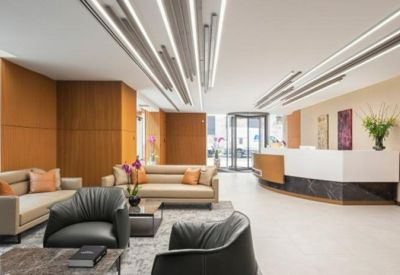 Bright reception area with wood-paneled walls, modern strip lighting, and comfortable lounge seating.