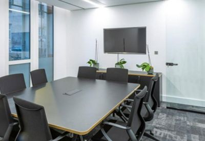 Professional meeting room with a large dark wood table, black chairs, and wall-mounted screen.