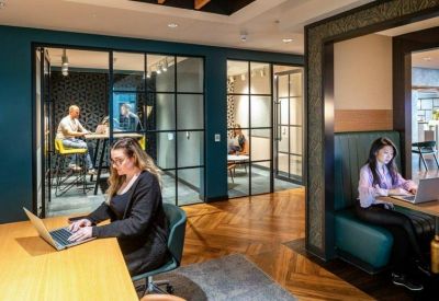 Private glass-partitioned booths and a central work table with people working.