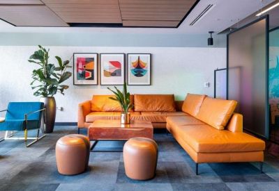 Lounge area featuring a large tan leather sectional sofa and abstract wall art.