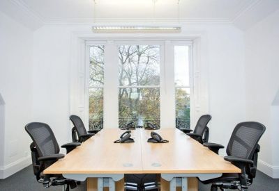 Small meeting room with a wooden table, four black chairs, and a large window.