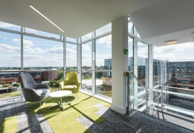 Bright corner breakout area with a green rug and lime green armchairs.