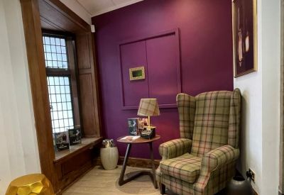 Cozy breakout nook with a purple feature wall and a classic tartan wingback chair.