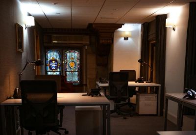 Professional workspace featuring modern desks and a large stained-glass window.
