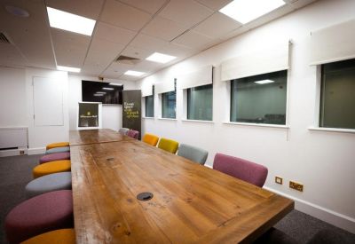 Bright boardroom featuring a long wooden table and colorful stool seating.