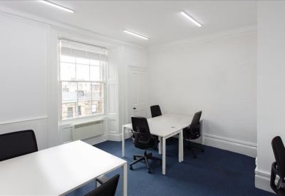 Bright four-person private office with large windows and blue carpet.