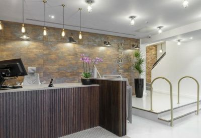 Reception desk with a wood-slat front, stone feature wall, and purple orchids.