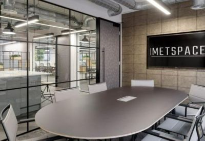 Professional meeting room with an oval table, grey chairs, and branded wall signage.