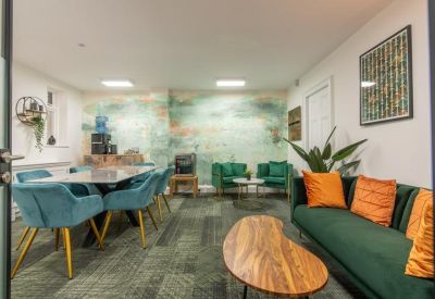 Communal lounge and dining area with teal chairs, green sofa, and a colorful feature wall.