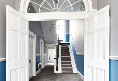 Grand hallway featuring a large decorative arched transom window above white double doors.