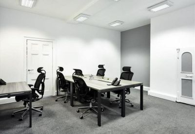Private office space with black ergonomic chairs and a large wooden shared desk.