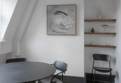 Cosy meeting area with a round black table, matching chairs, and open wooden shelving.