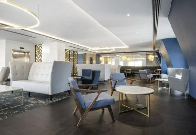 Stylishly furnished reception lounge area with blue velvet chairs and contemporary lighting.