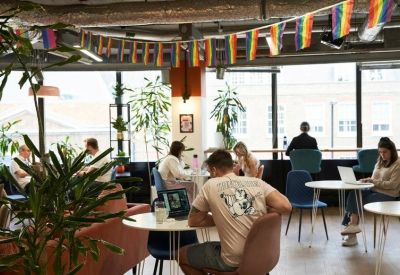 Coworking space featuring rainbow bunting, wooden tables, and people working on laptops.