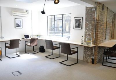 Bright office space featuring a long white workstation desk and ergonomic chairs.