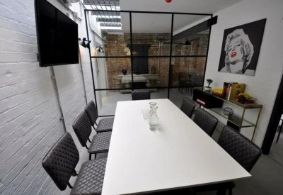 Modern meeting room with a white conference table, black chairs, and glass partition.