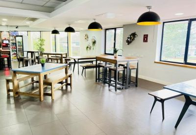 Modern café area with high tables, wooden benches, and industrial-style pendant lighting.