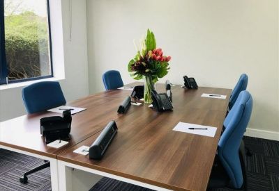 Four-person private office with a wooden desk and a colorful floral centerpiece.