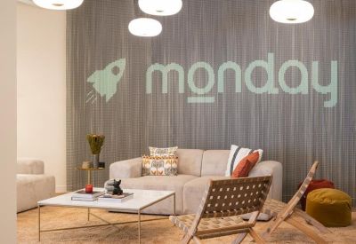 Branded reception lounge with a gray wood-paneled wall, plush beige sofas, and a white coffee table.
