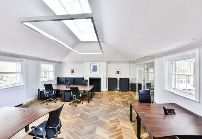 Open-plan workspace with parquet flooring, wooden desks, and an overhead skylight.