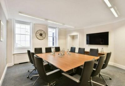 Modern conference room with a large wooden table and black ergonomic chairs.