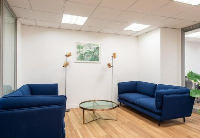 Bright lounge area with two navy blue sofas, a round coffee table, and wood-style flooring.