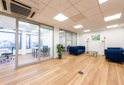 Spacious breakout area with blue seating and glass-partitioned private offices.